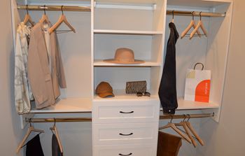 A walk in closet with white drawers and shelves